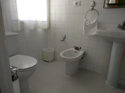 a white bathroom with a toilet and a sink at Hostal Buenavista in San Ciprián