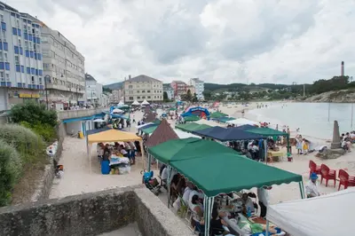 a crowd of people on a beach with umbrellas at Hostal Buenavista in San Ciprián