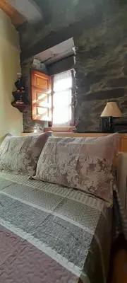 a bedroom with a bed with a stone wall at Casa de Abril 1 in San Cristóbal de Valdueza