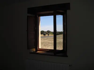 an open window with two horses in a field at La Candela in Rabanal del Camino