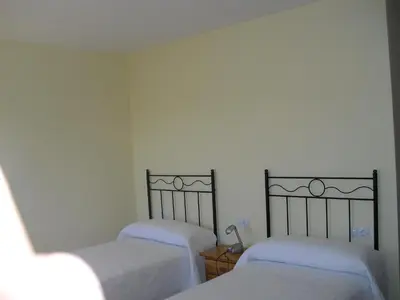 two beds in a room with white sheets at La Candela in Rabanal del Camino