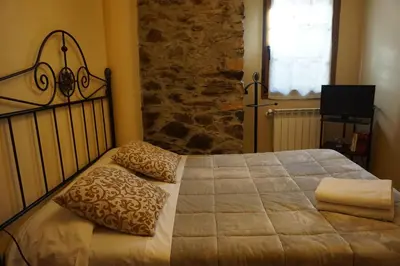 a bedroom with a large bed with a stone wall at Casa Morrosco in Molinaseca
