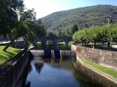 a bridge over a river with trees and a mountain at Casa Morrosco in Molinaseca