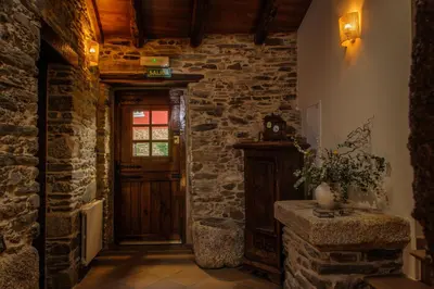 a hallway with a wooden door and a stone wall at Casa Grande do Soxal in Cesuras