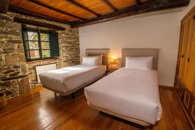 two twin beds in a room with a stone wall at Casa Grande do Soxal in Cesuras