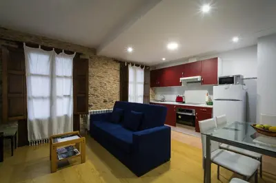 a living room with a blue couch and a kitchen at Apartamento con balcón in Viveiro