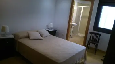 a bedroom with a bed and a chair and a window at Apartamento con balcón in Viveiro