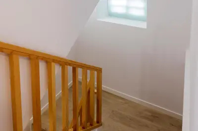 a stairway with a wooden rail and a window at Pensión Rua Nova in Santiago de Compostela