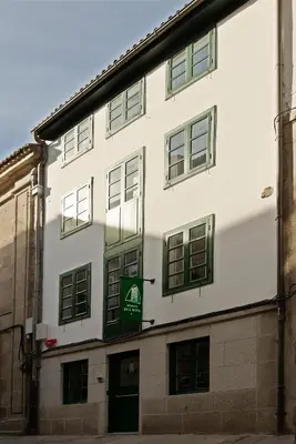 a white building with a green sign on it at Pensión Rua Nova in Santiago de Compostela