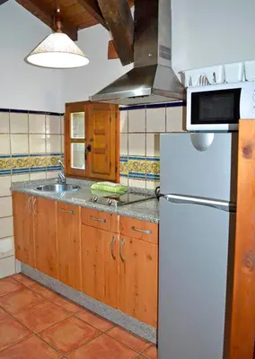 a kitchen with a white refrigerator and a sink at Pedrazales Rural in Pedrazales