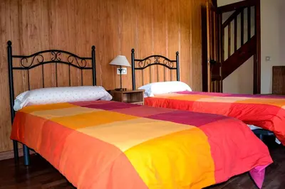 two beds with colorful blankets in a room at Pedrazales Rural in Pedrazales