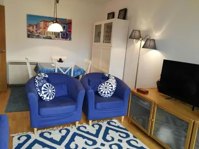 a living room with two blue chairs and a television at San Ciprián Playa y Mar by I Love Norte in San Ciprián