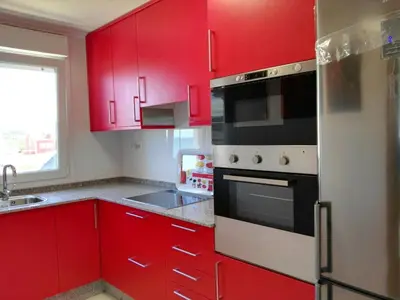 a red kitchen with red cabinets and a refrigerator at San Ciprián Playa y Mar by I Love Norte in San Ciprián