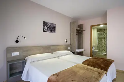 a bedroom with two beds and a bathroom at Albergue Pensión Cima do Lugar in Arzúa