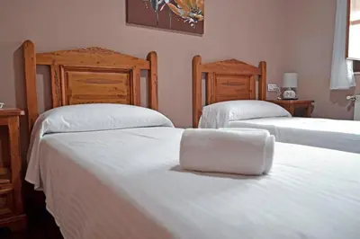a bedroom with two beds with white sheets and wooden headboards at Hotel Rural La Casa de Irene in Lubián