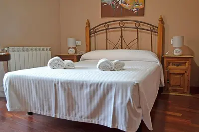 a bedroom with a white bed with two towels on it at Hotel Rural La Casa de Irene in Lubián