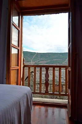 a bedroom with a large window looking out at the water at Hotel Rural La Casa de Irene in Lubián