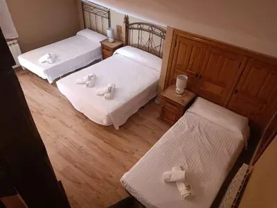 three beds in a room with white sheets at Hotel Rural La Casa de Irene in Lubián