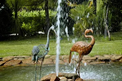 two birds standing in the water near a fountain at Pazo de Monterrei in Ourense