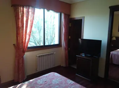 a bedroom with a tv and a window and a bed at Pazo de Monterrei in Ourense
