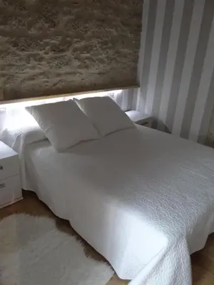 a white bed with two pillows in a bedroom at Casa do Forno in Castro de Oro