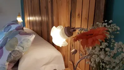 a lamp next to a bed with a vase of flowers at Casa da Curuxeira in Santiago de Compostela