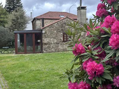 a stone house with pink flowers in front of it at Casa Boado in Boimorto