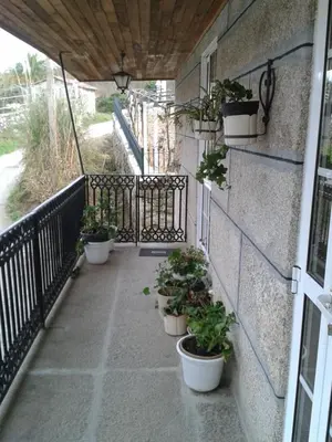 a balcony with potted plants on the side of a building at Apartamentos Turísticos Casa dos Pulidos in Olás de Villariño