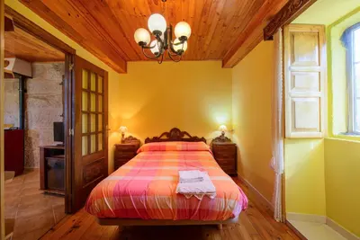 a bedroom with a bed and a chandelier at Apartamentos Turísticos Casa dos Pulidos in Olás de Villariño