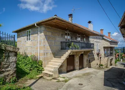a brick house with a balcony and stairs on it at Apartamentos Turísticos Casa dos Pulidos in Olás de Villariño