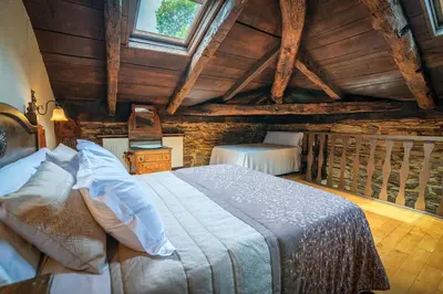 a bedroom with a large bed in a attic at Apartamentos Rurales Casa Riveras in Santa Eulalia de Oscos