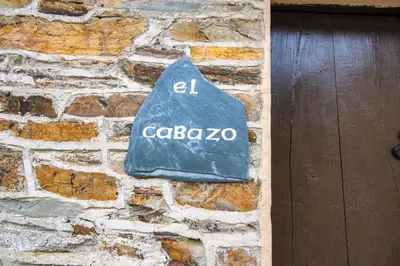 a sign on a stone wall next to a door at Apartamentos Rurales Casa Riveras in Santa Eulalia de Oscos