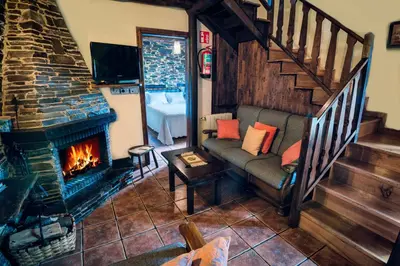 a living room with a couch and a fireplace at Apartamentos Rurales Casa Riveras in Santa Eulalia de Oscos