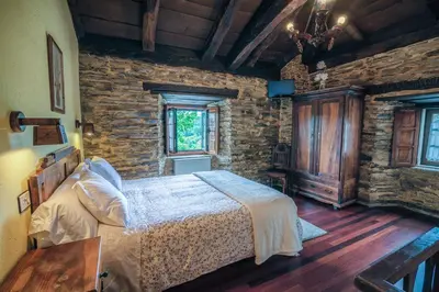 a bedroom with a bed and a stone wall at Apartamentos Rurales Casa Riveras in Santa Eulalia de Oscos