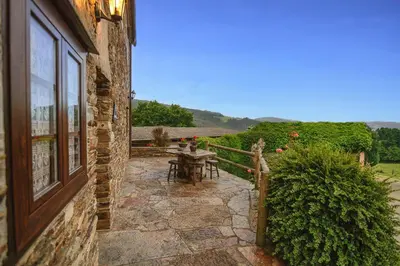a stone patio with a table and a window at Apartamentos Rurales Casa Riveras in Santa Eulalia de Oscos