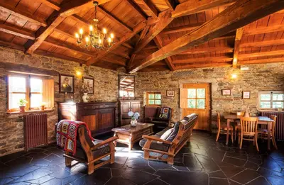 a living room with wooden ceilings and a table and chairs at Casa Lourán in Monfero