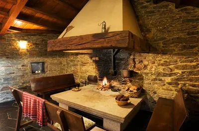 a stone room with a table and a fireplace at Casa Lourán in Monfero