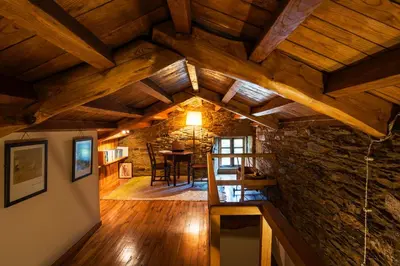 an attic room with a stone wall and wooden ceilings at Casa Lourán in Monfero