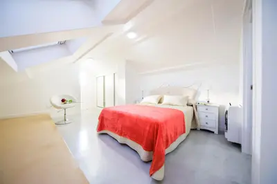 a white bedroom with a bed with a red blanket at Rueiro 17 in A Coruña