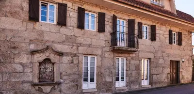 an old stone building with white doors and windows at Casa Cruceiro in Barcela