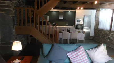 a living room with a blue couch and a kitchen at Casa Do Grilo in Monfero