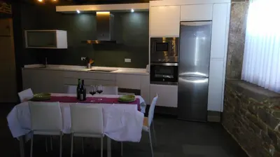 a kitchen with a table with chairs and a refrigerator at Casa Do Grilo in Monfero