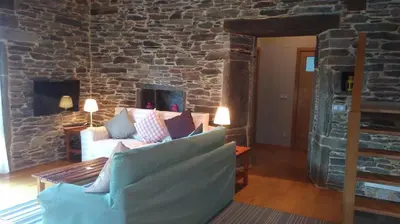 a living room with a couch and a stone wall at Casa Do Grilo in Monfero