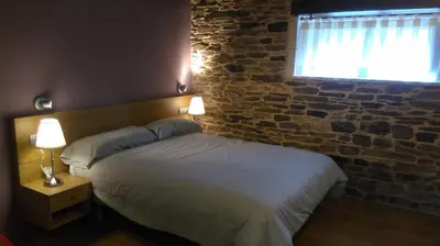 a bedroom with a bed and a brick wall at Casa Do Grilo in Monfero