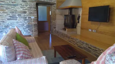 a living room with a stone fireplace and a tv at Casa Do Grilo in Monfero