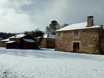 a stone building with snow on the ground at Casa Do Grilo in Monfero