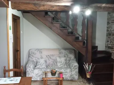 a living room with a couch and a staircase at Apartamento La Corrada in Santa Eulalia de Oscos