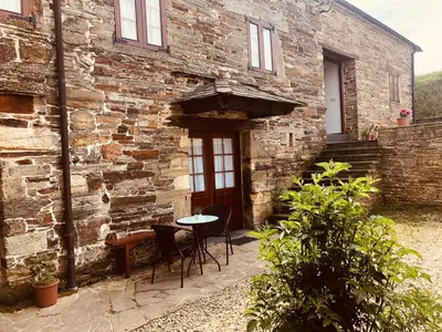 a stone building with a table and chairs in front of it at Apartamento La Corrada in Santa Eulalia de Oscos