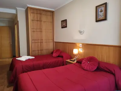 two beds in a hotel room with red sheets at Hostal Ponte Dos Santos in Ribadeo