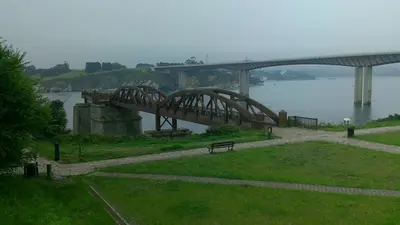 a bridge over a body of water with a bench at Hostal Ponte Dos Santos in Ribadeo